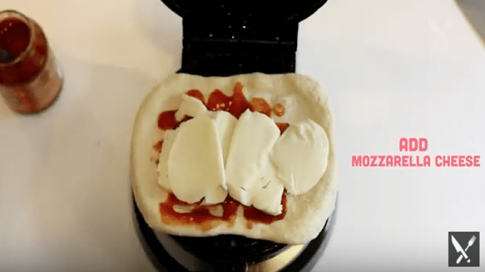 Wenn du den Teig auf das Waffeleisen gelegt hast, fügst du die Tomatensauce sowie den Mozzarella-Käse hinzu.