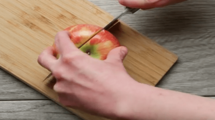Statt den Apfel in der Mitte durchzuschneiden, schneidest du den Apfel bei diesem Trick rechts knapp neben dem Kerngehäuse ein.