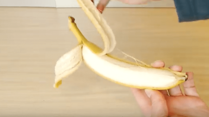 Nun schälst du die Banane zur Hälfte von unten nach oben.